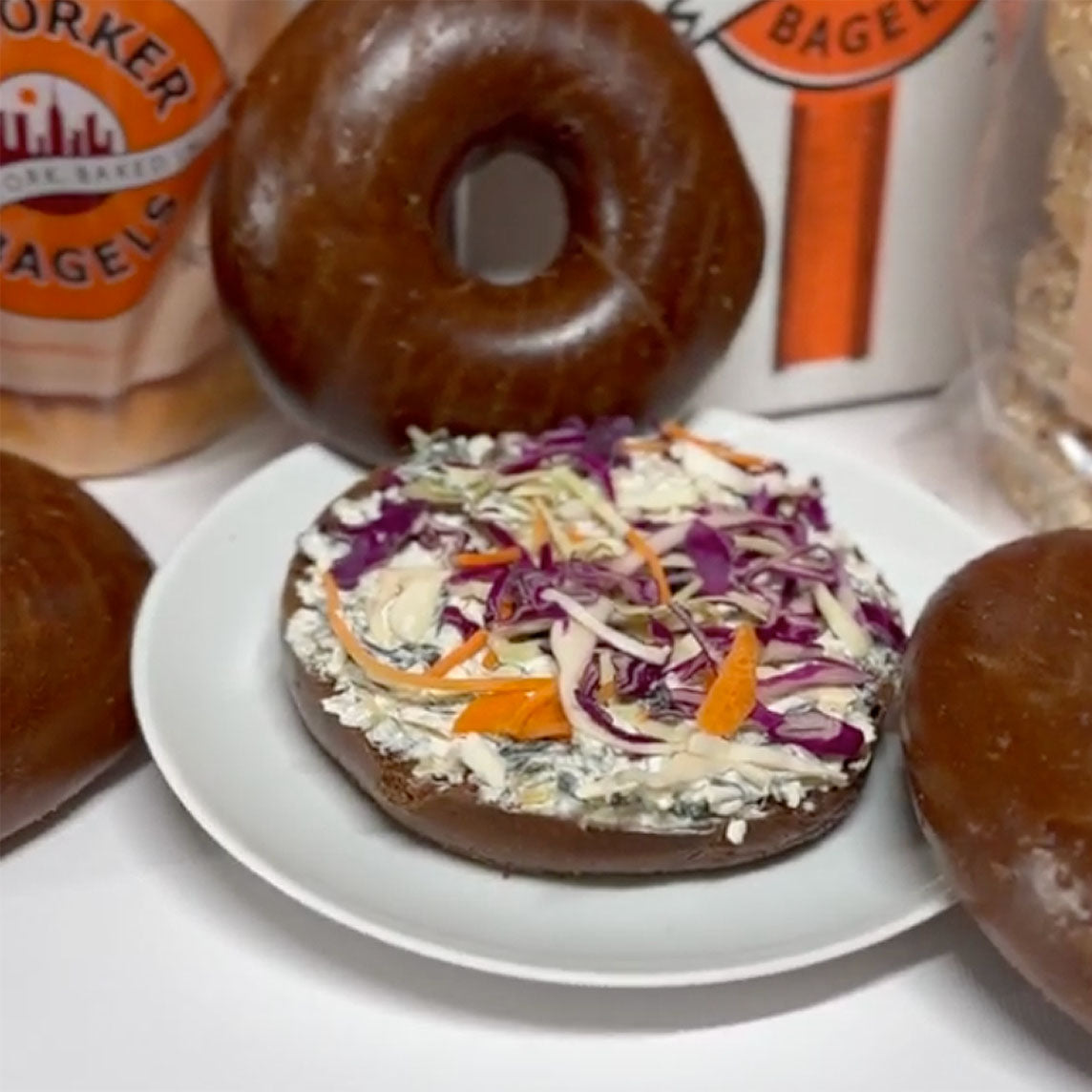 A sliced pumpernickel bagel with spinich dip and cole slaw.