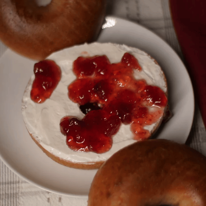 whole wheat bagel with cream cheese and raspberry jelly